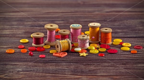 Collection of spools  threads in yellow-red colors on a grunge wooden box