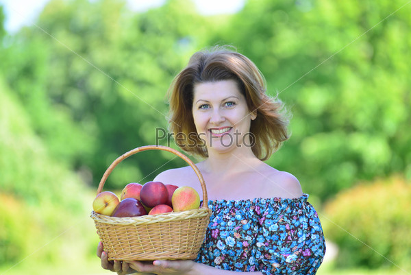 An adult woman with a basket of fruit in the park