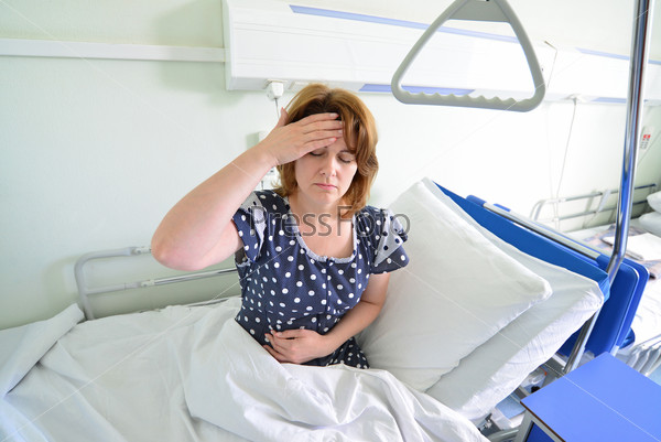 Female patient with headache on a bed in hospital ward