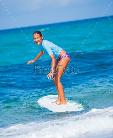 Teenage girl in blue learning to surf