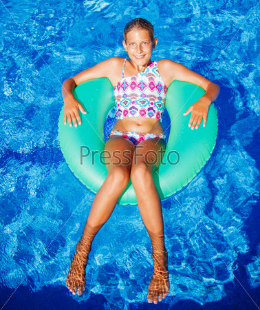 Funny girl swims in a pool in an green life preserver