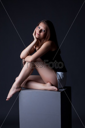 Smiling model sitting on cube in studio