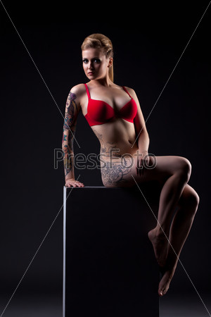 Attractive tattooed model sitting on cube