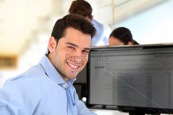 Smiling trader in front of desktop computer