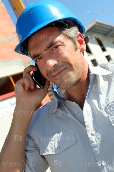 Engineer with blue security helmet talking on mobile phone