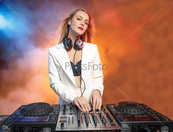 Beautiful blonde DJ girl on decks on the party on the background of orange smoke