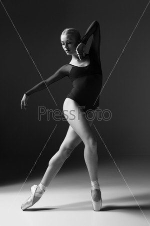 young beautiful dancer posing on a studio gray background. black and white photo