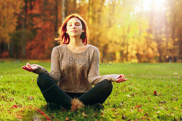 Young attractive female meditate in park. Outdoor shot