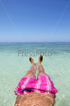 Closeup of man\'s feet floating in blue lagoon water