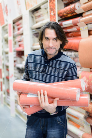 man holding a roll of wallpaper in the store
