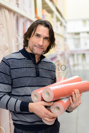 man holding a roll of a wallpaper in the store