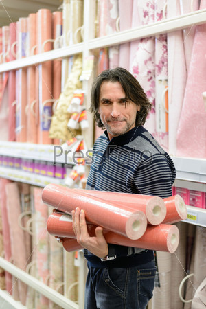 man holding a roll of a wallpaper in the store