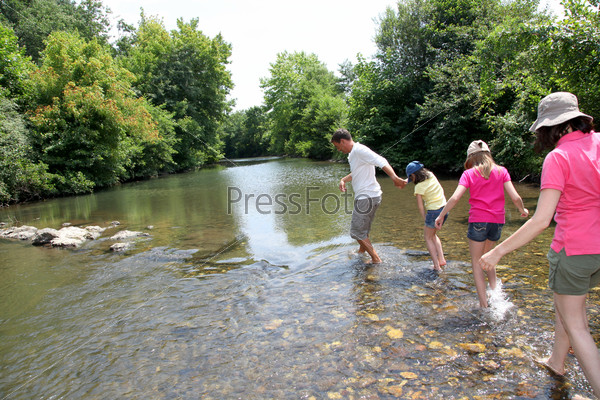 Family crossing river in summer, stock photo