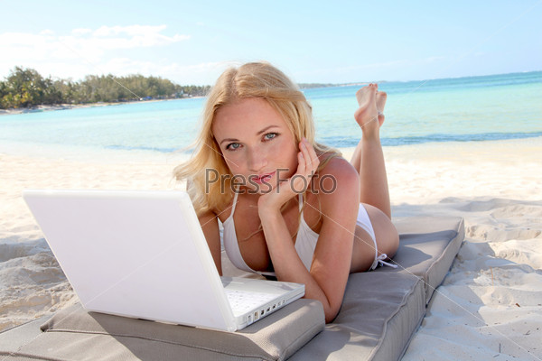 Beautiful blond woman at the beach with laptop computer