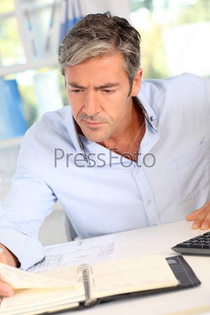 Handsome office worker writing notes on agenda