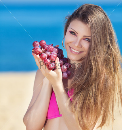 Portrait of beautiful woman with grapes in hands in summer outdoor