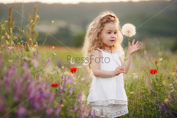 Portrait of a cute little girl in sunny summer day at green nature background. Summer joy - lovely girl blowing dandelion.