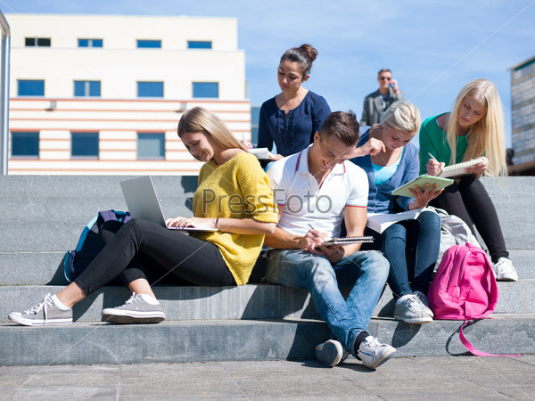Group portrait  of happy  students outside sitting on steps have fun