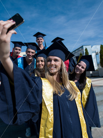 Capturing a happy moment.Students group  college graduates in graduation gowns  and making selfie photo