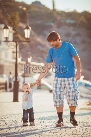 Father playing with his son on the pier near yacht club in summer. Outdoor
