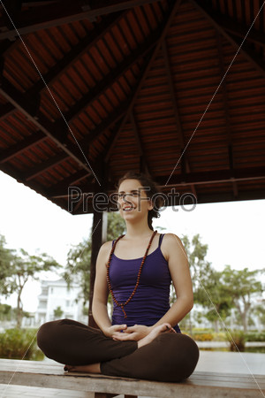 Smiling girl sitting in pavilion in lotus position