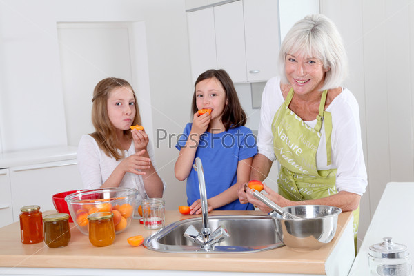 Senior woman making apricot jam with grandkids