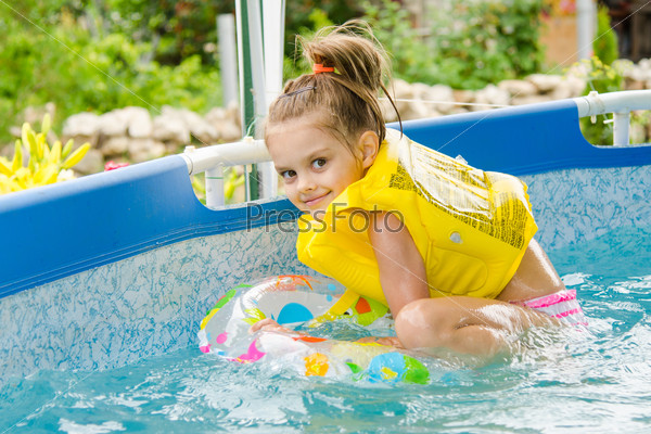 Cheerful girl bathing trying to get into the swimming circle