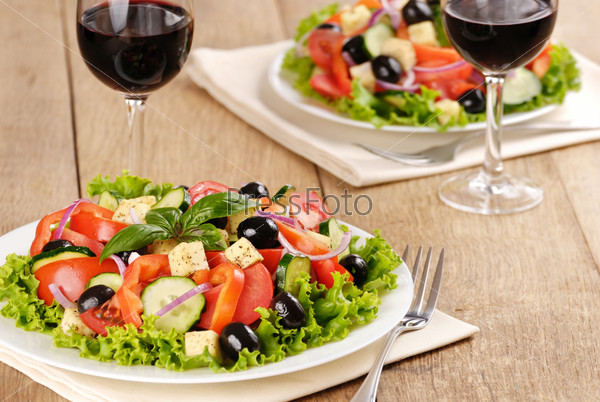 Vegetable salad and glass of red wine on the oak table