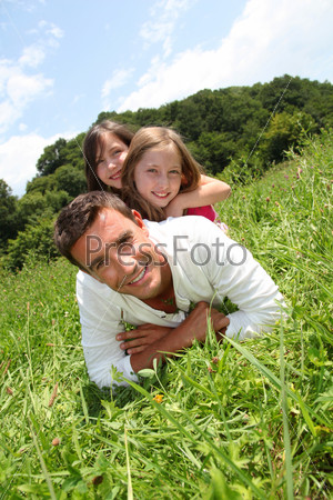 Man lying down in park with girls on his back