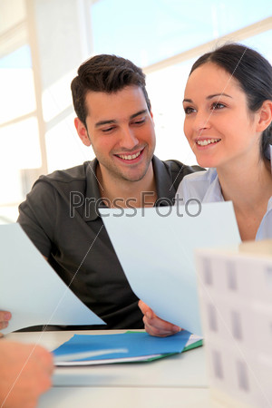 Happy young couple signing property purchase contract