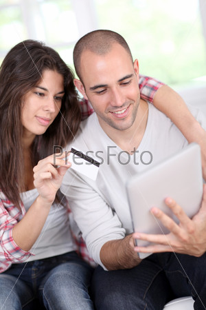 Young couple doing online shopping using electronic tablet