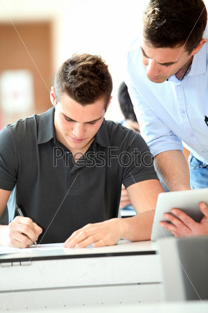 Teacher with tablet helping student with exam