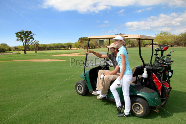 Couple on golf course with cart, stock photo