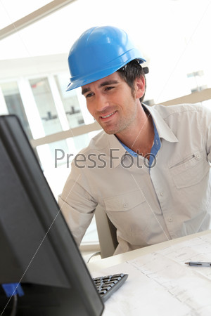 Smiling architect in office working on desktop computer