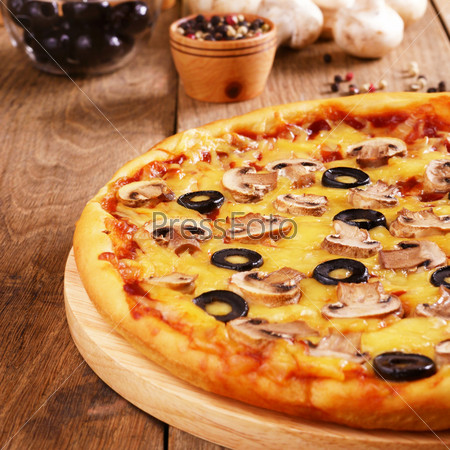 Mushroom pizza on the kitchen table with olives and spices