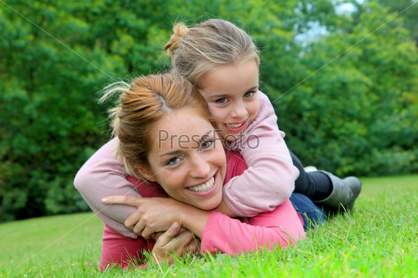 Little girl and mother laying on grass in park