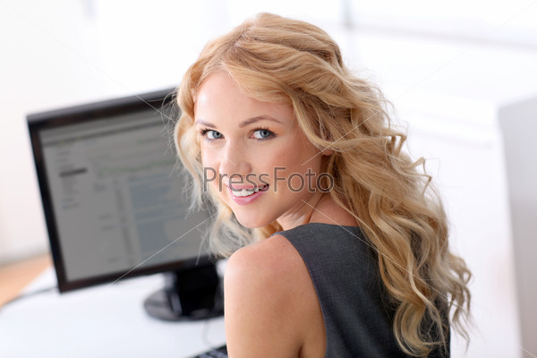 Portrait of beautiful woman sitting in front of desktop computer