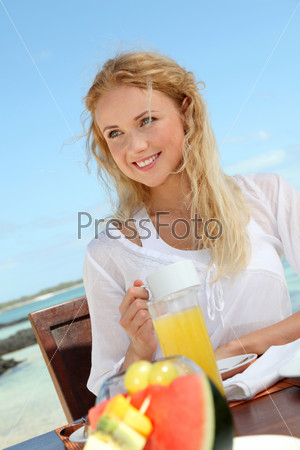 Beautiful woman having breakfast by the sea