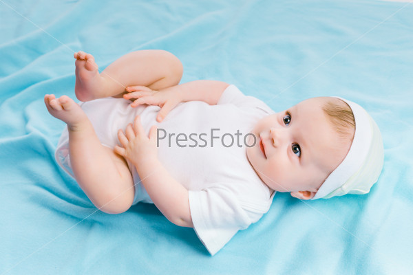 Cute baby in hat lying on a blue blanket
