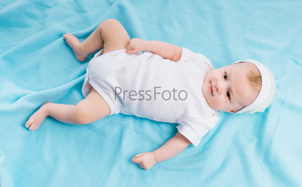 Cute baby in hat lying on a blue blanket