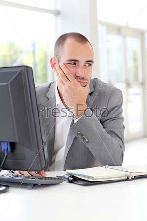 Businessman in front of desktop computer with thoughtful look
