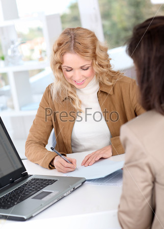 Beautiful woman signing contract in insurance company