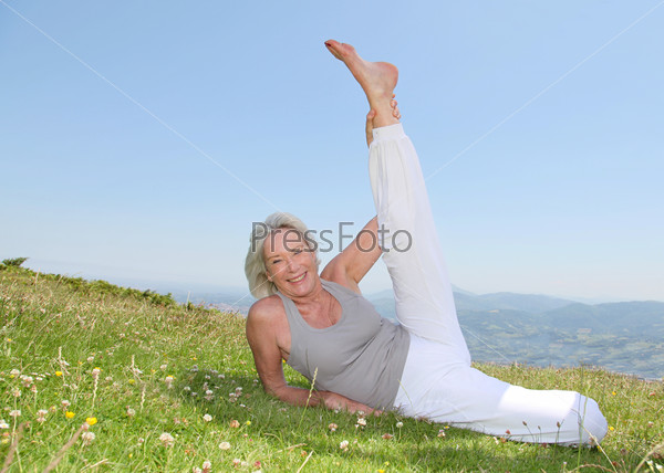Senior woman doing stretching exercises in countryside