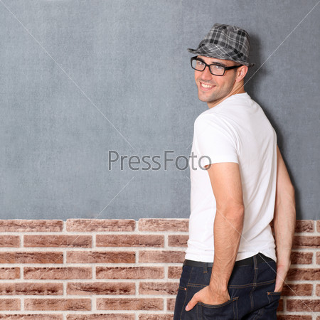 Trendy guy leaning on brick wall