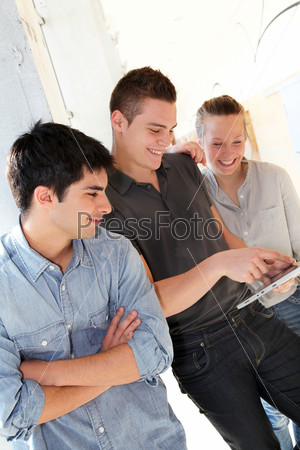 Friends in school corridor using electronic tablet