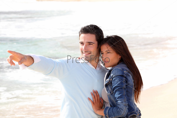 Couple at the beach, man showing something to girl