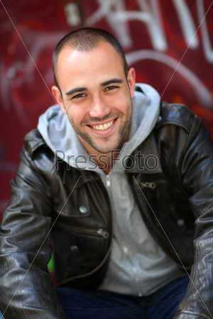 Smiling young man sitting in street