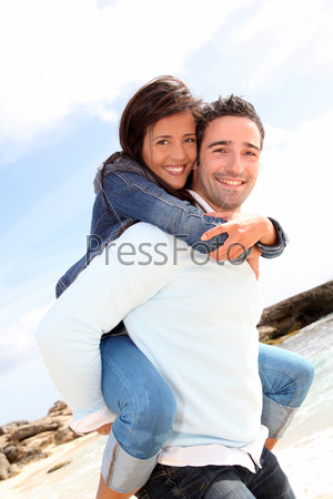 Man giving piggyback ride to girlfriend on the beach