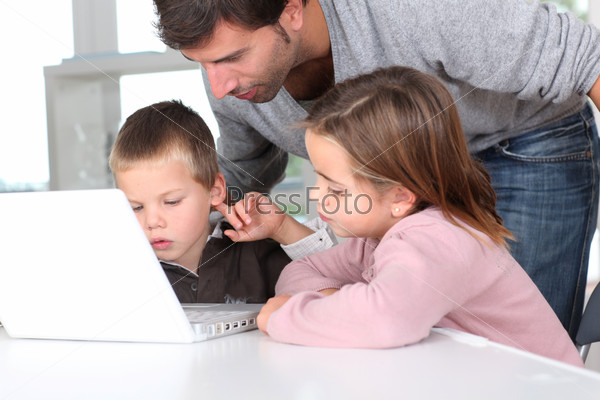 Man teaching kids how to use laptop computer, stock photo