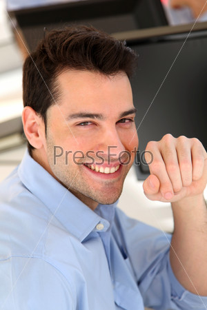 Smiling trader in front of desktop computer